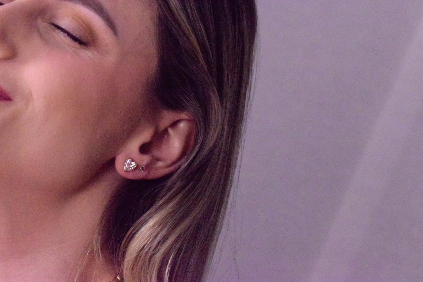 Minimal background featuring Goldmacher moissanite heart solitaire studs on the model