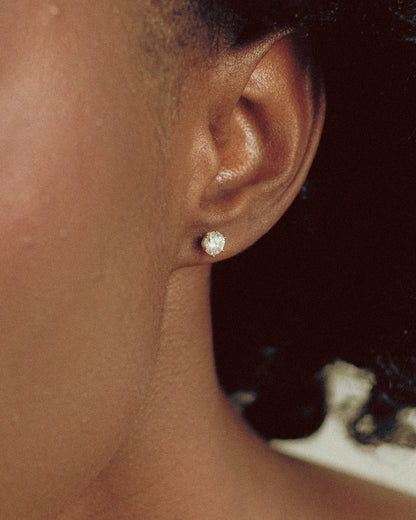 Close-up of Goldmacher model wearing Zenith moissanite stud earrings with secure screw-back closure and classic six-prong setting